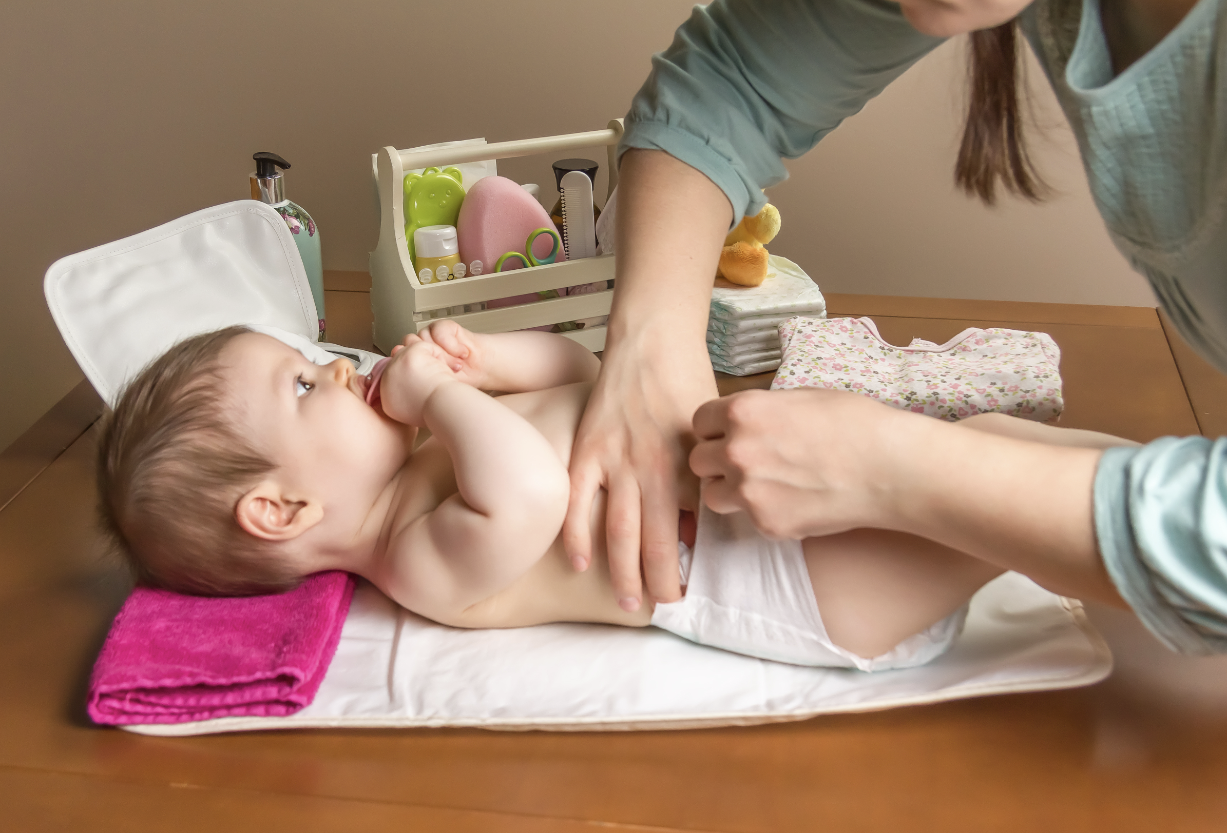 A mother putting a diaper on her son.
